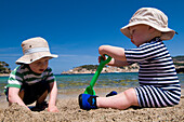 Baby boy (6-11 months) and toddler (2-3) playing in sand on beach, Majorca, Ballearic Islands, Spain