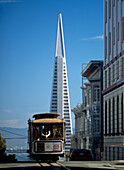 Cable car going down Washington Street on Nob Hill with the Trans-America Pyramid behind, San Francisco, California