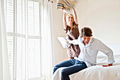 Young couple at a pillow-fight in a bedroom, Hamburg, Germany