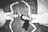 Two Women in Fashionable Dresses Laying on Ground, High Angle View