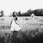 Woman in White Dress Looking Over Shoulder While Walking in Field