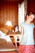 Mädchen in einem Hotelzimmer hält ein Brettspiel, Naturhotel Grafenast, Am Hochpillberg, Schwaz, Tirol, Österreich