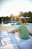 Woman sitting on a sunlounger beside a hotel pool, Ramatuelle, Provence-Alpes-Cote d'Azur, France