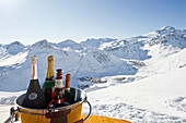 Bottles of champagne in a cooler, Snow-capped mountains in the background, Tignes, Val d Isere, Savoie department, Rhone-Alpes, France