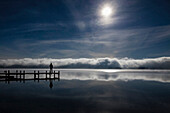 Mann blickt auf Starnberger See, Roseninsel im Nebel, Morgenstimmung mit Mond, Oberbayern, Deutschland