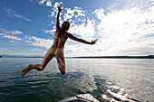 Junge Frau springt in Starnberger See, Oberbayern, Deutschland