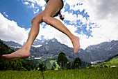 Young woman jumping barefoot over meadow, Eng, Ahornboden, Karwendel mountains, Tirol, Austria, Europe