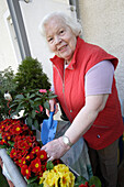 Eine alte Frau pflegt ihre Balkonblumen in einem Altersheim, München, Oberbayern, Bayern, Deutschland, Europa