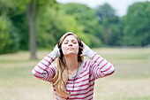 Portrait of a woman with closed eyes listening to music in the park