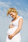 Blonde pregnant woman enjoying her pregnancy at the beach