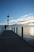 Wellington State Park - The silhouette of a man on dock watching sunrise over Newfound Lake in Bristol, New Hampshire USA