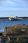Wooden lobster traps and boat in Nauset Harbor, Orleans, Cape Cod, MA, USA
