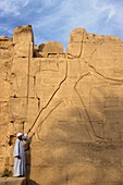 guide showing a carving of Thutmose III on the Seventh Pylon, Karnak, Luxor, Thebes, Egypt, Africa