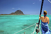 Young woman with a sarong on a bow of the saling boat, Tamarin bay, Le Morne moutain, Mauritius, Indian Ocean