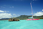Catamaran moored at l'île aux Bénitiers close to a coral rock, Mauritius, Indian Ocean