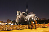 France, Paris, 4th, Ile de la Cité, the cathedral Notre Dame and la Seine at night, tourist looking the padlocks of love at the Archevêché Bridge