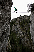 Junger Mann balanciert über eine Highline zwischen zwei Felsen, Oberammergau, Bayern, Deutschland, Europa
