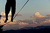Junger Mann balanciert über eine Longline bei Sonnenuntergang, Auerberg, Bayern, Deutschland, Europa