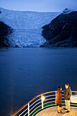 Paar an Deck von Kreuzfahrtschiff MS Deutschland, Reederei Peter Deilmann, vor dem Italienischen Gletscher im Dämmerlicht, Chilenische Fjorde, Magallanes y de la Antartica Chilena, Patagonien, Chile, Südamerika