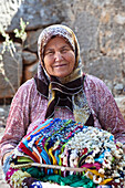 Old turkish woman selling souvenirs at Kalekoy castle, Simena, lycian coast, Mediterranean Sea, Turkey
