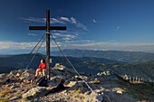 Hiker at the summit cross on top of the Geierkogel, Saualpe, Carinthia, Austria, Europe