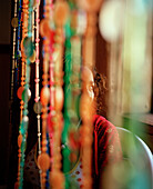 Young woman behind glass bead draperies, Bar Benfica, Cova Figuera, south eastern Island of Fogo, Ilhas do Sotavento, Republic of Cape Verde, Africa