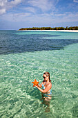 Eine junge Frau hält einen roten Seestern an einem Traumstrand im Punta Frances Parque Nacional Nationalpark, Isla de la Juventud, Kuba, Karibik