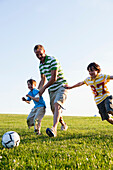 Father and Two Sons Playing Soccer