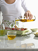 Woman pouring olive oil over roast dish. AAOilGuideOpener