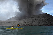 Auf dem Weg zur Arbeit. Männer paddeln von Matupi zum Vulkan, um Eier zu suchen, Tavurvur Vulkan bei Tag, Rabaul, Ost-Neubritannien, Papua Neuguinea, Pazifik