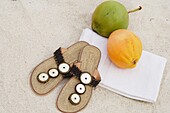 Pair of tongs on white sand and coconut