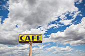 Road sign in large black lettering on a yellow background. Wikieup, Arizona, USA. Clouds gathering in sky., Cafe sign against cloud filled sky