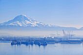 Shrouded in winter smog, Commencement Bay with Mount Rainier National Park  in the background. Tideflats that once formed the delta of the Puyallup River. Commencement Bay's history of industry and shipping has led it to designation as a Superfund Cleanup