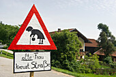 Selbstgemachtes Straßenschild, zeigt einer alten Frau bei Straßenüberquerung, Höslwang, Chiemgau, Bayern, Deutschland