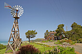 Westernmill in front of wooden house with garden at Navarro, Mendocino, California, USA, America