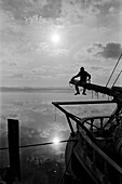 Sailor Sitting on Pole on Sailboat