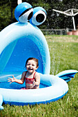 Young Girl in Red Bathing Suit Sitting in Small Pool