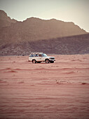 Geländewagen bei Sonnenuntergang in der Wüste, Wadi Rum, Jordanien, Naher Osten, Asien