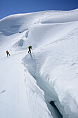 Zwei Bergsteiger überqueren große Gletscherspalte, Piz Palü, Graubünden, Schweiz