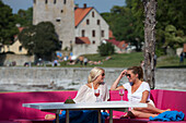 Two young women enjoying drinks and sunshine at the trendy Kallis Beach Club, Visby, Gotland, Sweden, Europe