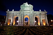 Night time view of the historic Puerta de Alcalá monument in the Plaza de la Independencia Madrid Spain