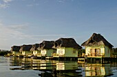 Thatch roofed bungalows on stilts in lagoon at Colon Island  Punta Caracol Hotel, Bocas del Toro, Panama, Caribbean, Central America