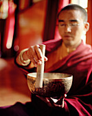 Monk Wangyal striking singing bowl and teaching concentration, convent Thagchockling, west of Leh, Ladakh, Jammu and Kashmir, India