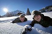 Zwei Jungen liegen im Schnee, Gargellen, Montafon, Vorarlberg, Österreich