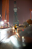 Safety deputy directing traffic at night at the worlds largest shipyard, Hyundai Heavy Industries (HHI) dockyard, Ulsan, South Korea