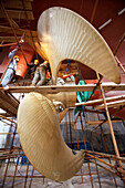 Chinese workers installing blades on a variable-pitch propeller, MAN Diesel delivers three components for propulsion: the engine, drive shaft and propeller, shipbuilding in the dry dock, Ouhua Shipyard at Zhoushan, Zhejiang province, China