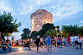 a busy evening at the illuminated white tower, symbol of the town of Thessaloniki, Macedonia, Greece