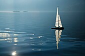 Sailing boat on an alpine lake with islands and reflections