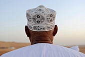 Middle East,Oman, Sharqiyah,Wahiba Sands,man wearing a hat watching the desert