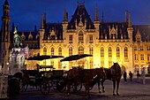 Provinciaal Hof and horse-drawn carriages, illuminated at night, Bruges, Belgium